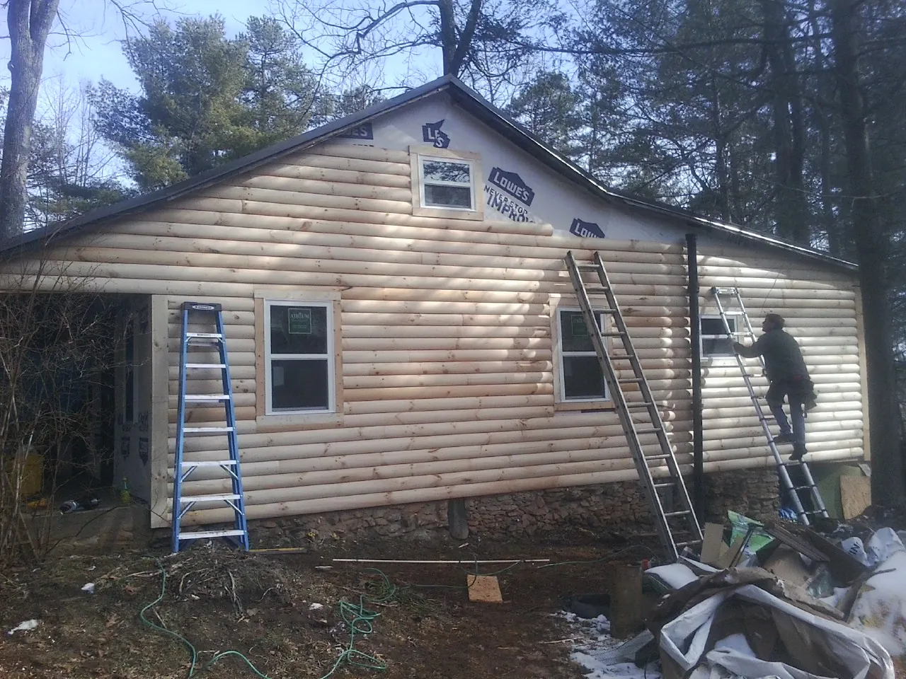 Ladders set against fresh log siding during an exterior remodel in Goshen