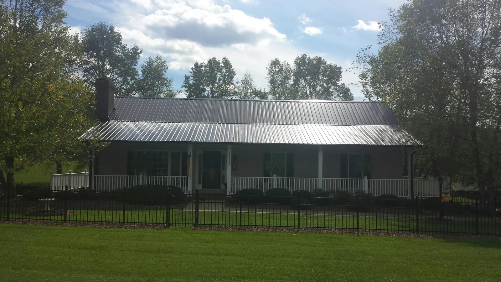Gray metal roof on a brick ranch with a full width front porch — Gutter Guard Installation work by our crew in Goshen